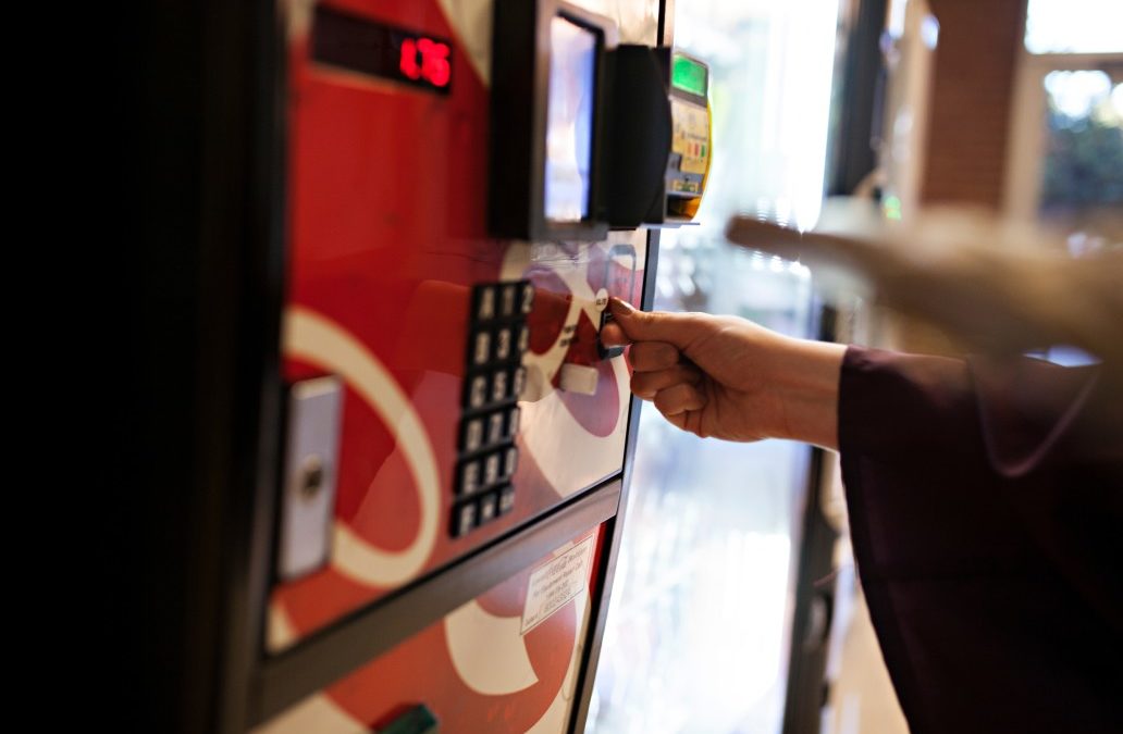 person putting coins in a soda vending machine